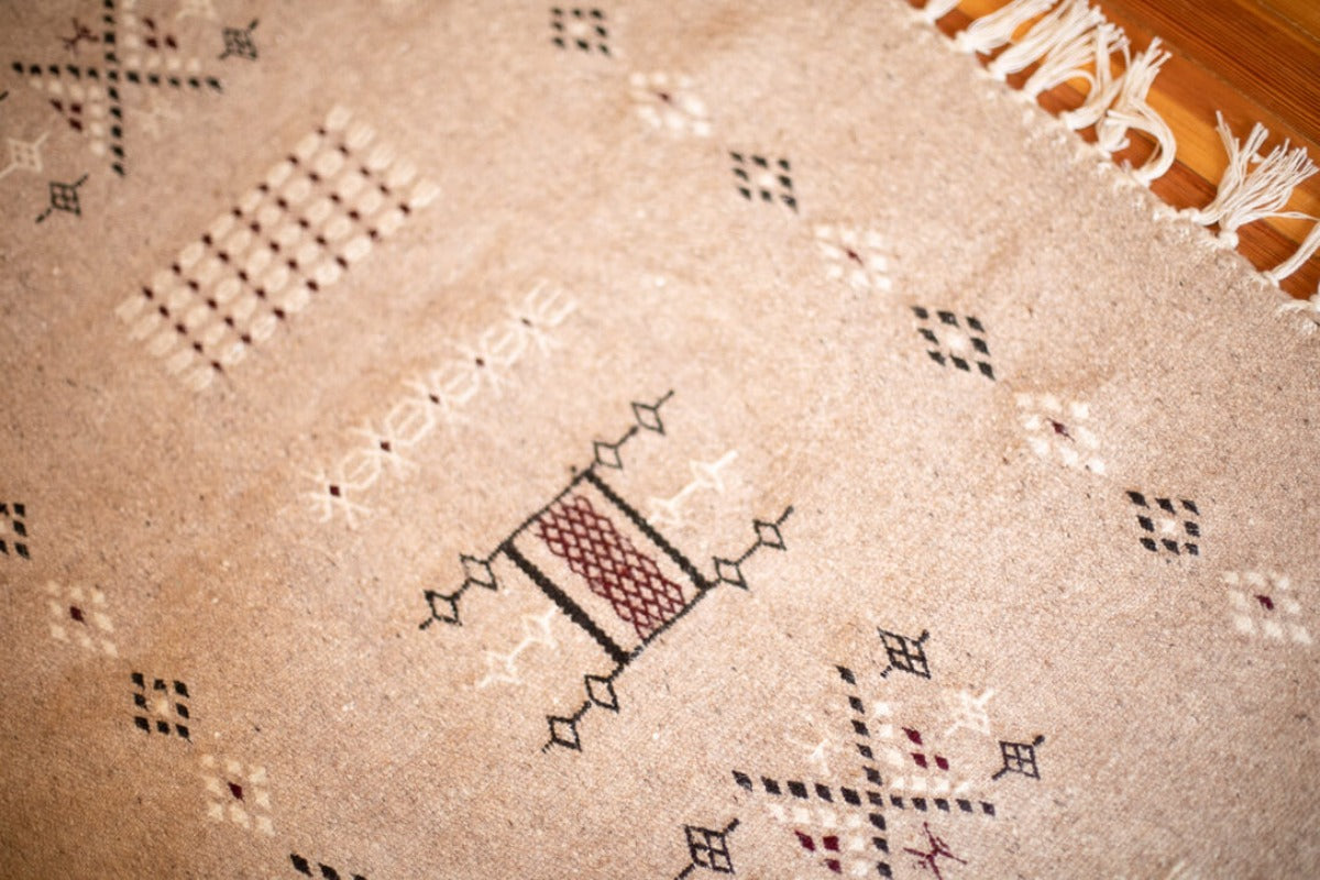 Close up of gray area rug with traditional motifs.