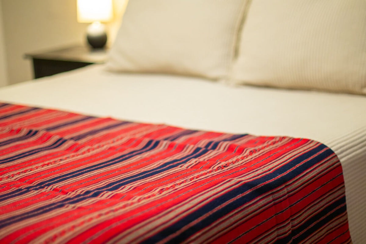 Bedspread on a bed with blue and red stripes