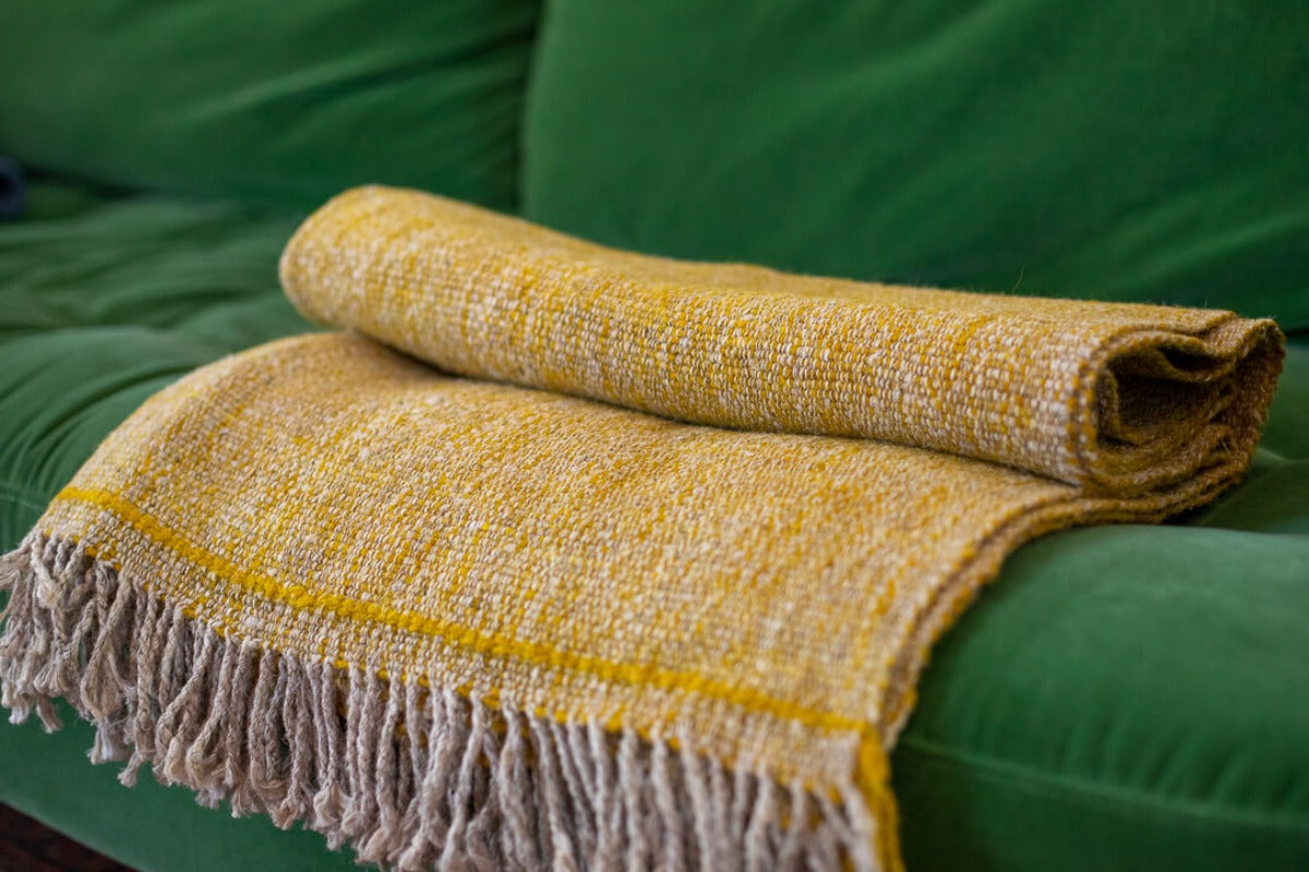 Folded yellow blanket on a green couch
