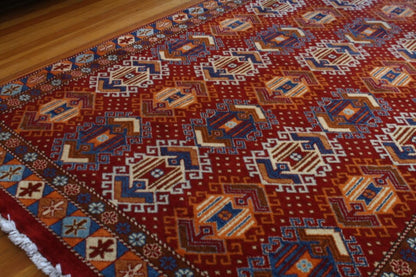 Red Kazak rug with blue and orange motifs.