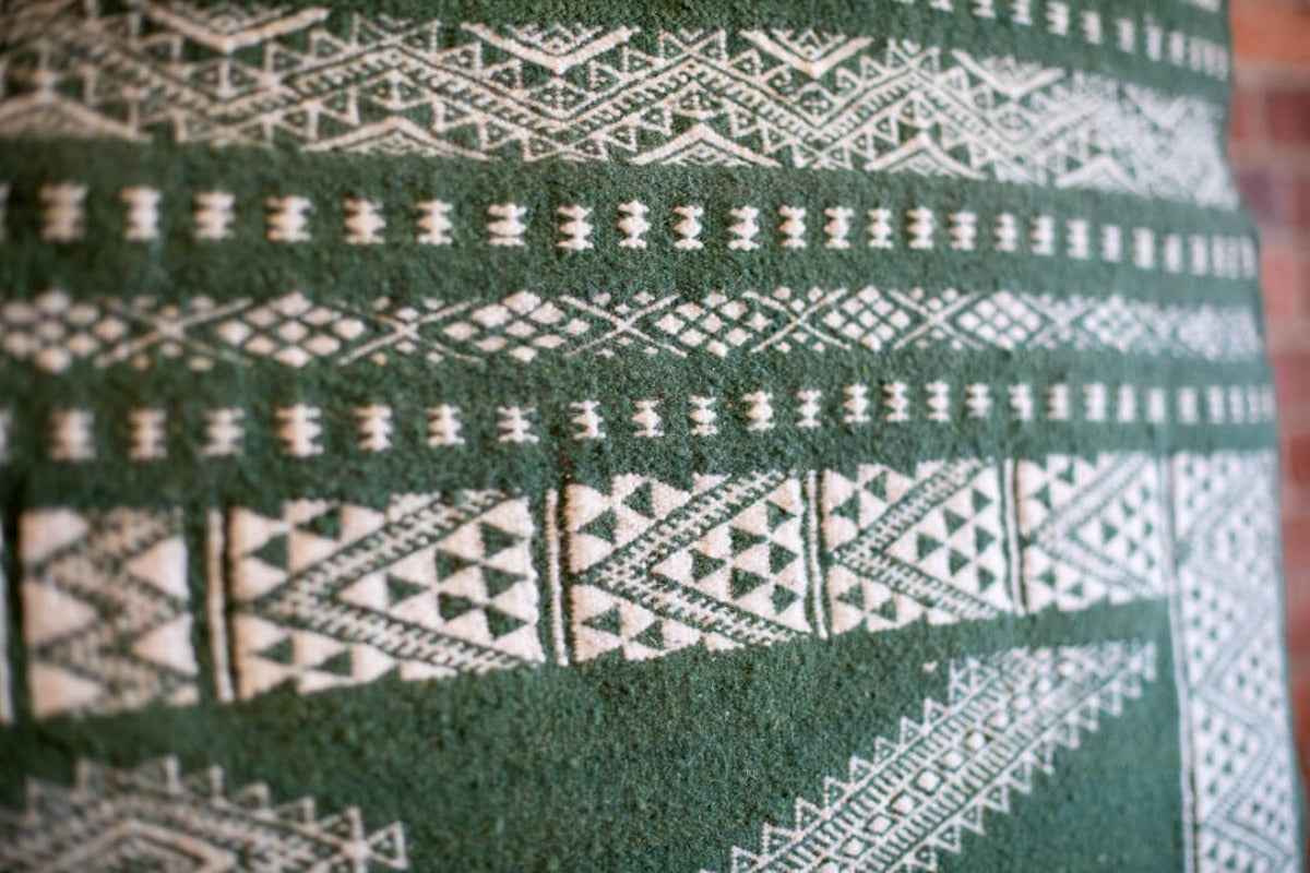 Monochrome green berber rug with geometric patterns. 