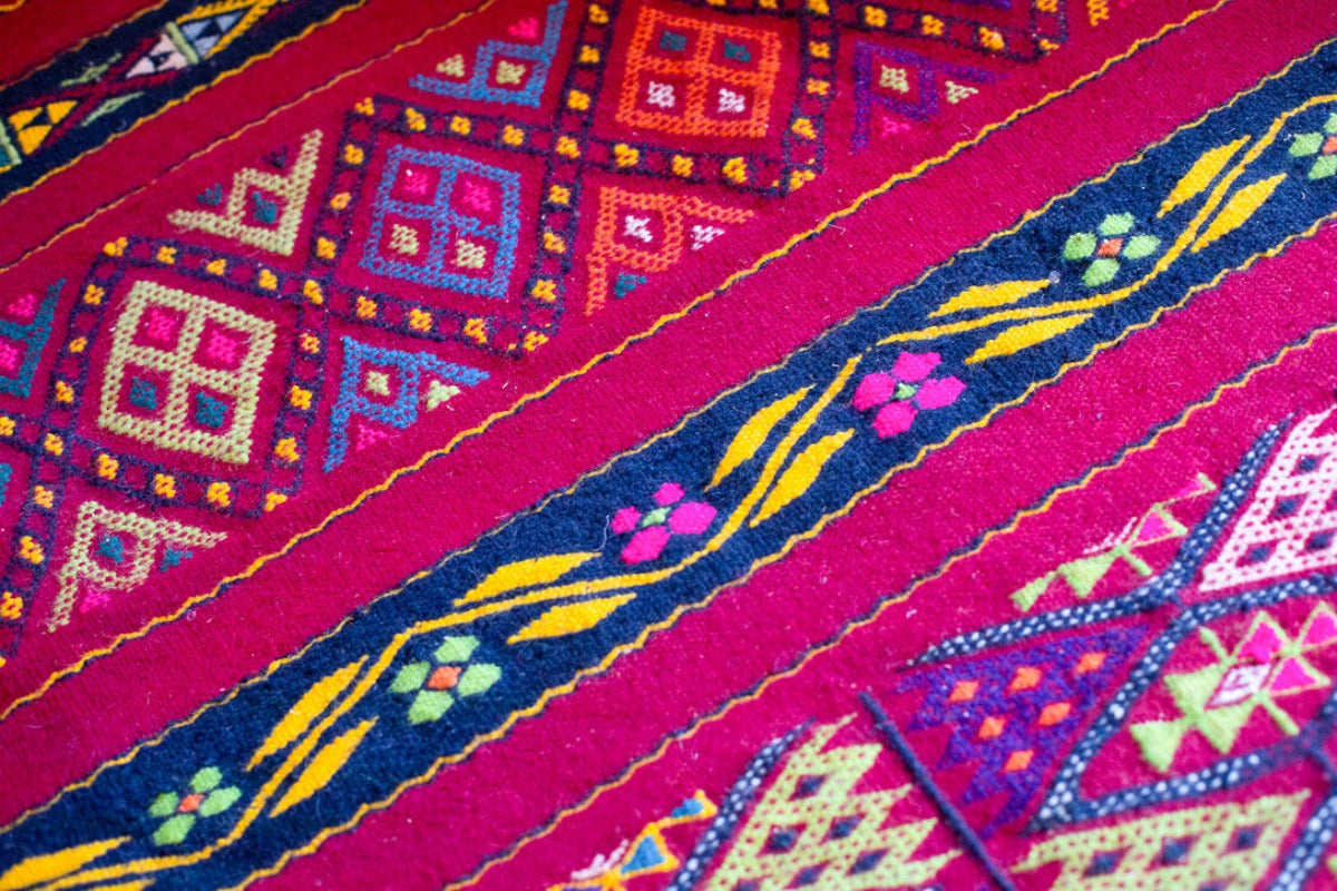 Red berber rug with geometric and flower patterns.