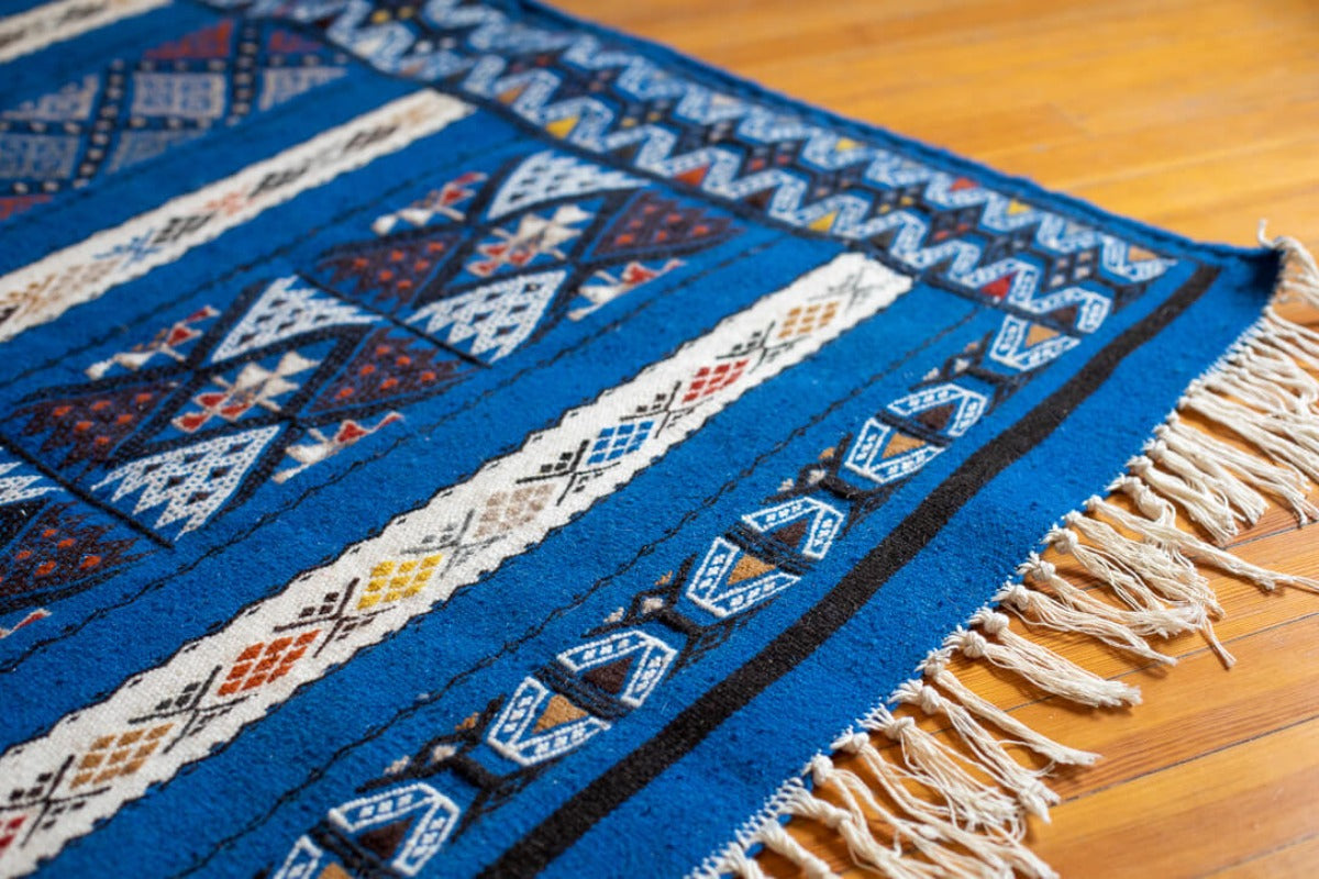 Tassels of flat weave rug with blue background and patterns
