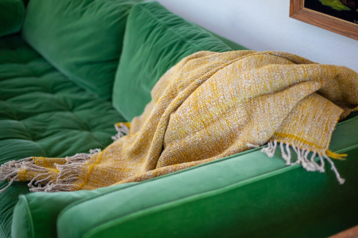 Yellow blanket layered on a green couch