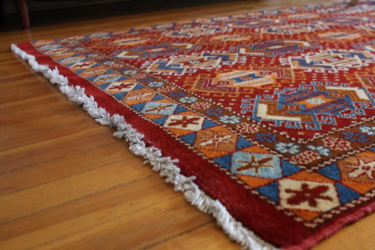 Red rug with blue and orange motifs.