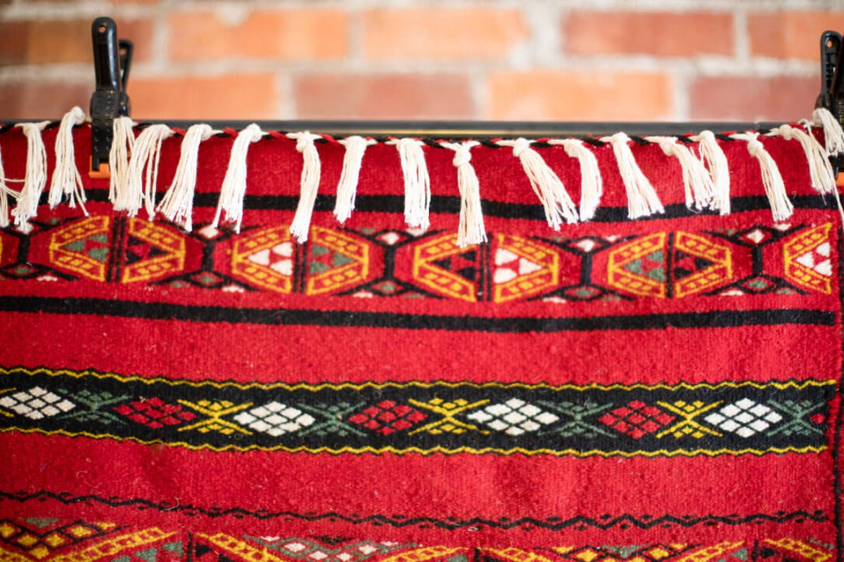 Close up of fringe and red rug with geometric patterns