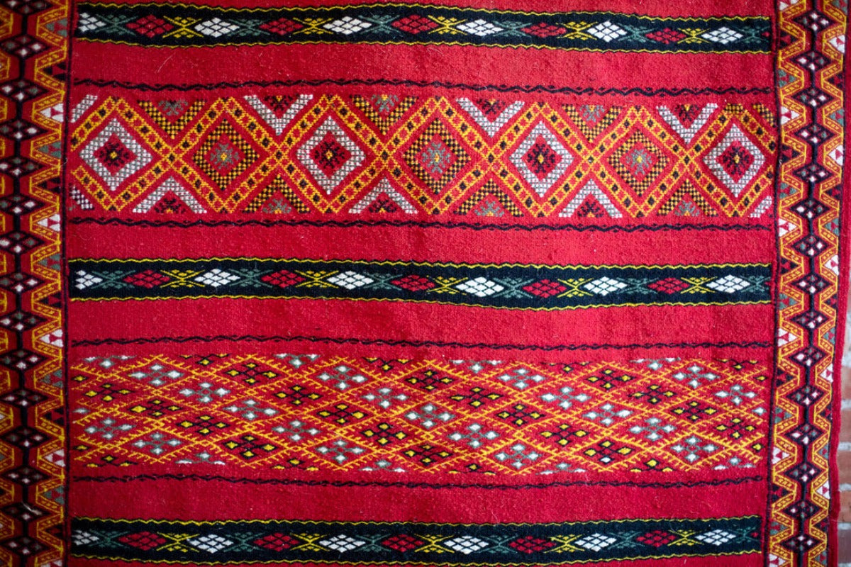 Red rug with yellow geometric patterns