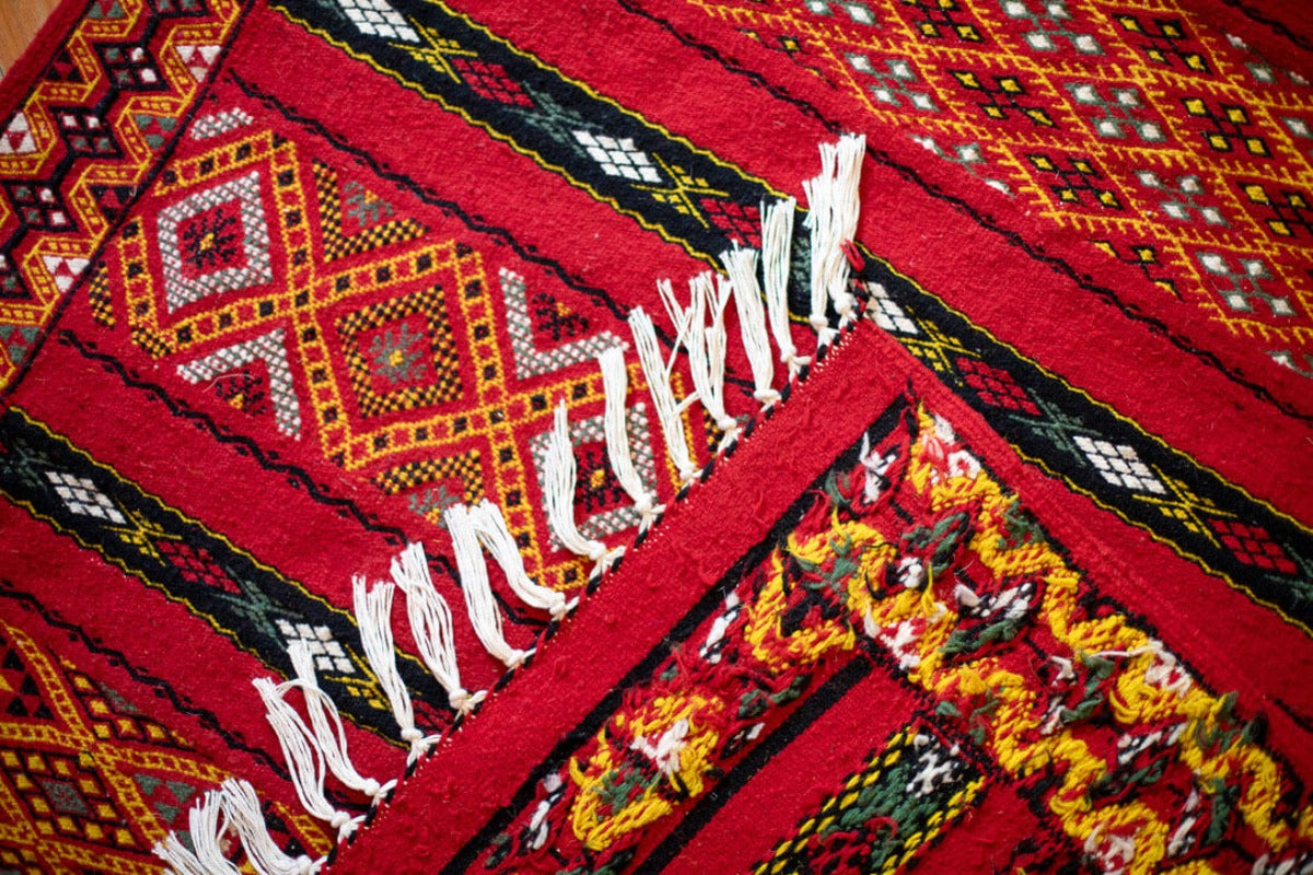 Front and back view of red rug with geometric patterns.