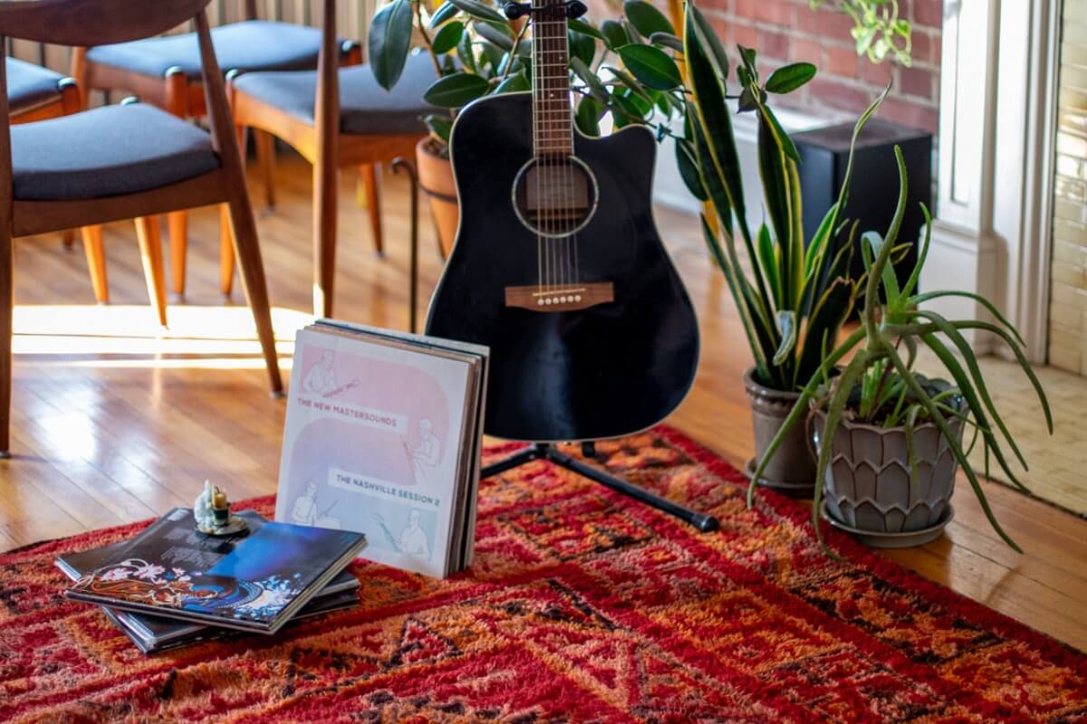 Guitar, plants, and records on rug